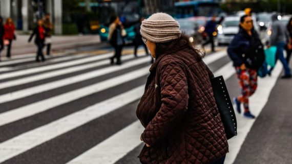mulher atravessando a rua com casaco e touca